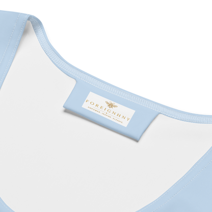 Close-up of a light blue and white garment with a visible brand label on a white background